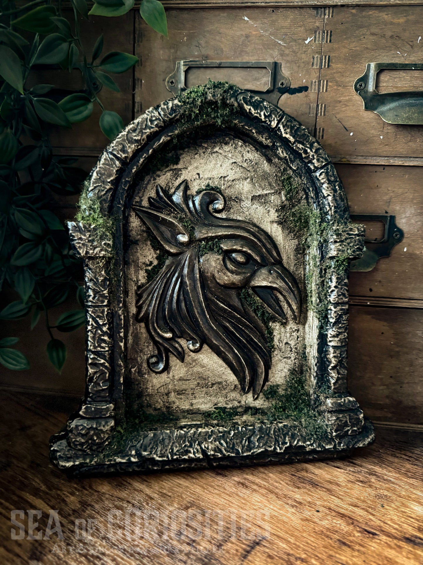 Decorative sculpted stone wall arched window with Griffin head, branded 'Sea of Curiosities'.