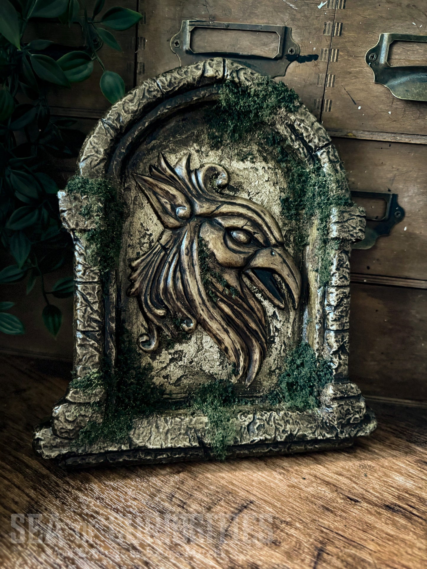 Decorative sculpted stone wall arched window with Griffin head, branded 'Sea of Curiosities'.