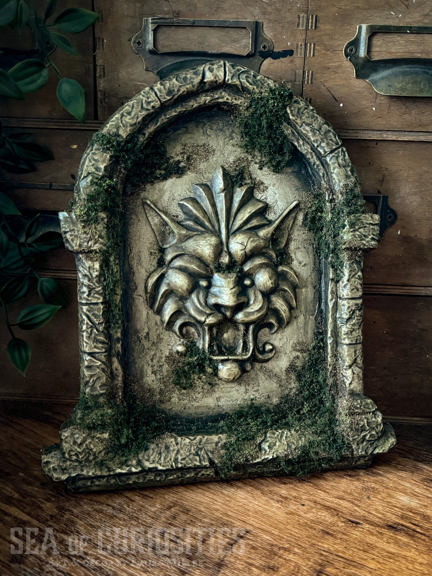 Decorative sculpted stone wall arched window with Lion head, branded 'Sea of Curiosities'.