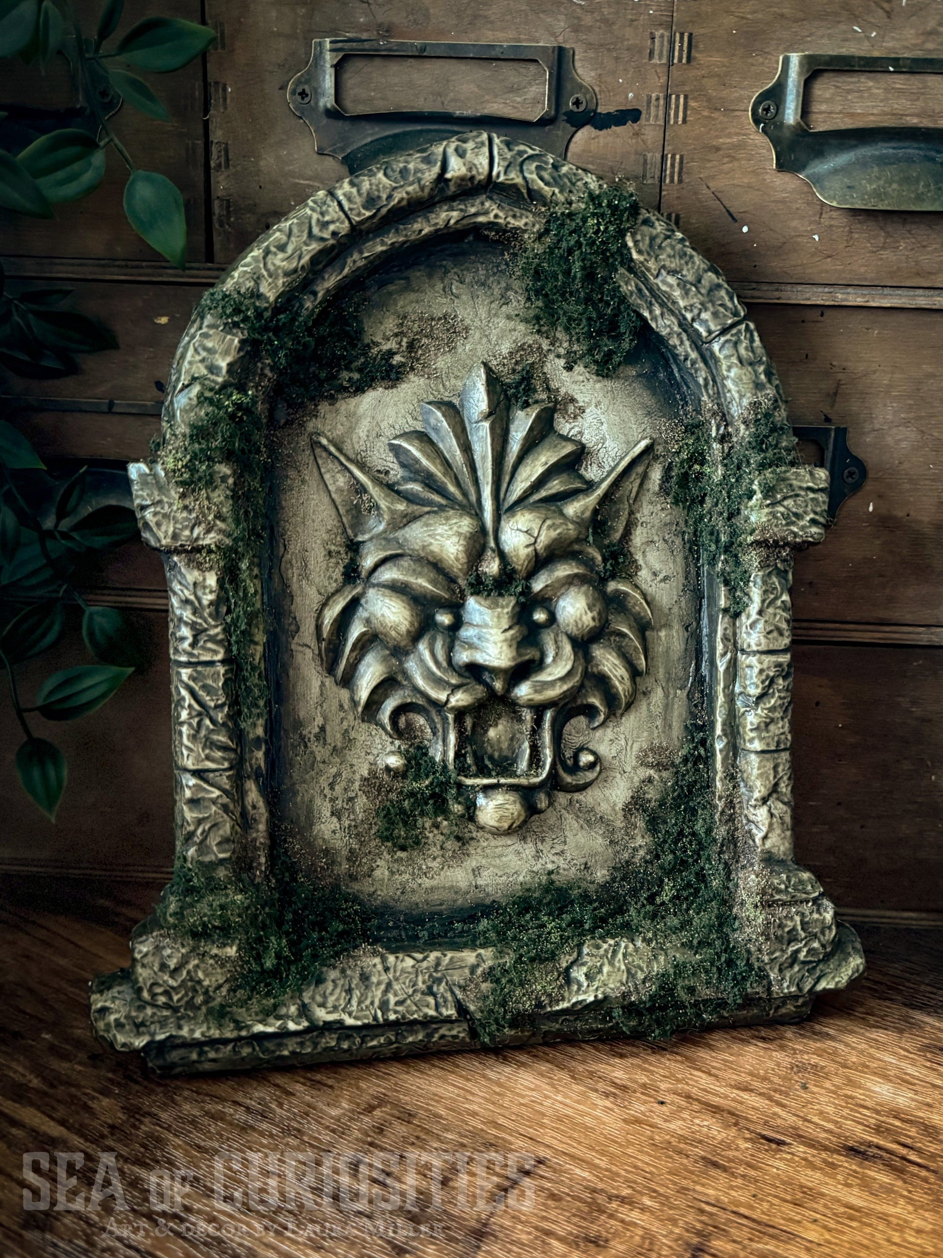 Decorative sculpted stone wall arched window with Lion head, branded 'Sea of Curiosities'.